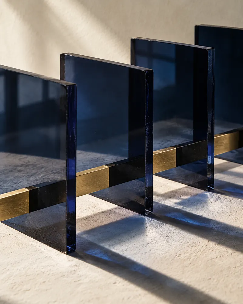 Cuatro planos de vidrio azul conectados por latón: estudio conceptual de marca.