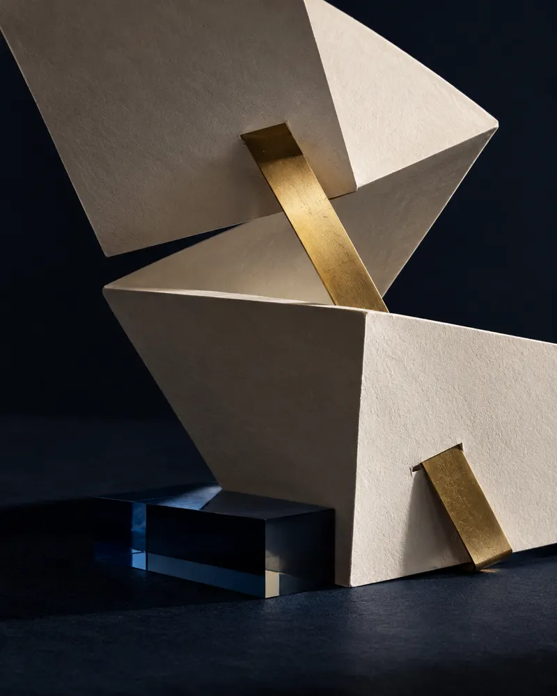 Papel marfil plegado y latón: estudio conceptual de marca sobre una misma dirección.